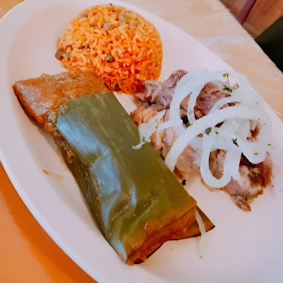 A Puerto Rican dish with pasteles, rice with gandules, and pernil topped with onions.